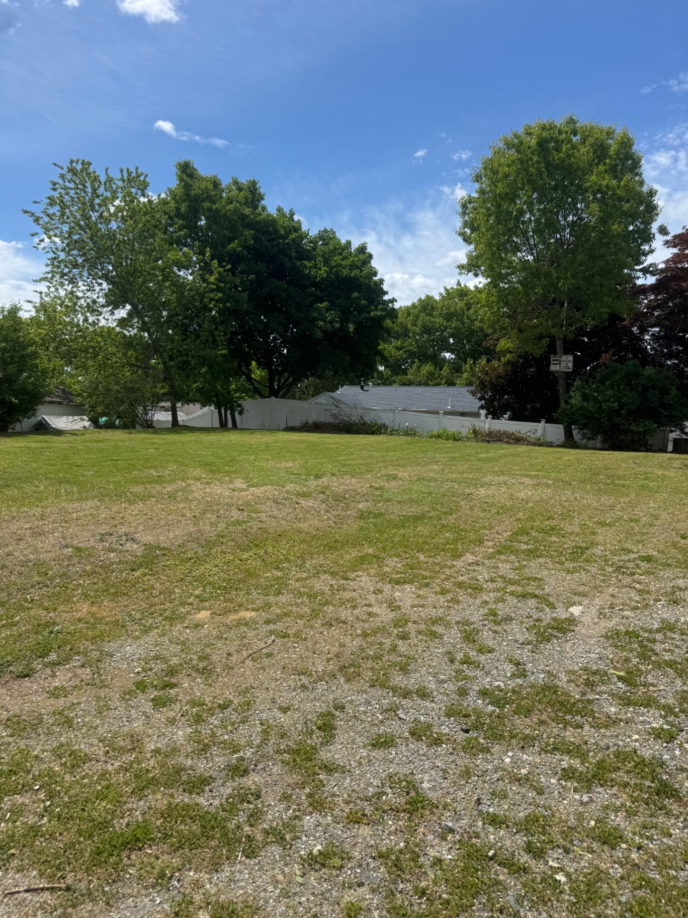 Large open lawn mowed along a white fence line